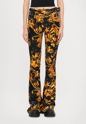Black flared pants with gold floral pattern, made of textured fabric. Features a unique belt with metal accents and a tailored fit.