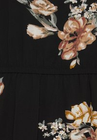 Svart tyg med blommönster som har beige och persikofärgade blommor, gröna löv och en strukturerad yta; veckad midjesömdetalj.