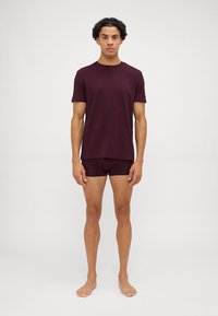 Bordowy bawełniany t-shirt i dopasowane szorty, krótki rękaw, okrągły dekolt, obcisły krój, gładka tekstura, noszone na boso.