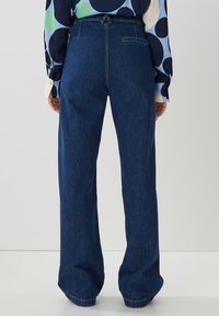 Högmidjade jeans i mörkblått med vida ben. Har en bakficka och subtila sömnadsdetaljer. Slät textur.