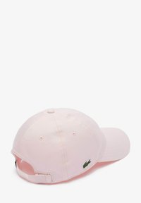 Casquette de baseball en coton rose avec une visière incurvée, fermeture à l'arrière et un petit logo de crocodile vert brodé sur le côté.