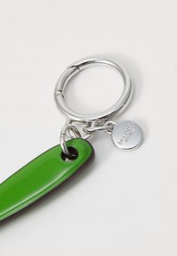 Porte-clés avec un charme en plastique vert et noir, comprenant un anneau en métal argenté brillant et un petit pendentif gravé.