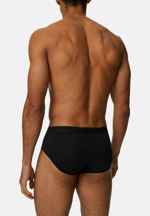 Slip in cotone nero con una morbida vita, design aderente e texture liscia. Cuciture visibili e stile minimalista senza fantasie.