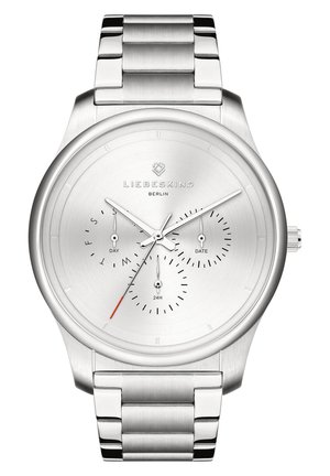 Sølv rustfrit stål ur med et minimalistisk design, der har en børstet urskive, tre underdials til dag, dato og 24-timers format samt et ledarmbånd.