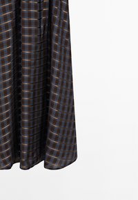 Brown plaid dress with blue and orange stripes, made of lightweight fabric. Features a flowing design and a rounded hemline.