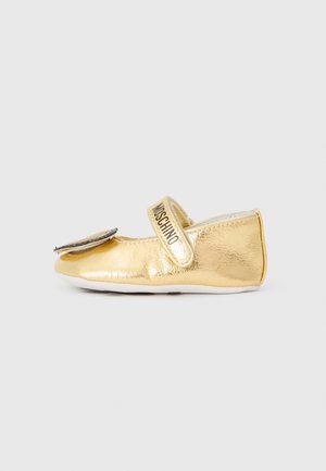 Gold metallic children's shoe with a flat design, Velcro strap, and a decorative flower accent on the toe. Smooth texture, minimal detailing.
