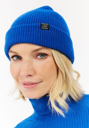 Blauwe geribbelde gebreide beanie met een omgeslagen boord en een zwart label met de tekst "PROTEST HOUSE OF SNOW." Zachte textuur en een snug fit.