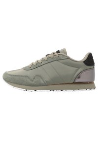 Chaussure de sport présentant un mélange de cuir vert lisse et de suède gris texturé, avec un accent en mesh noir et un talon métallique argenté. Semelle blanche tachetée.