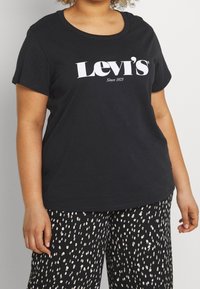 Camiseta de algodón negra con cuello redondo y mangas cortas, que presenta un logo blanco de "Levi's Desde 1873" en el frente.