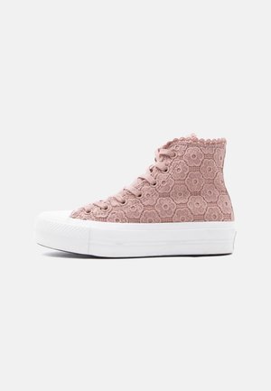 High-Top-Sneaker mit rosa blumenspitzigem Obermaterial aus Spitze und dicker weißer Gummisohle sowie Zehenschutzkappe, seitlich auf weißem Hintergrund betrachtet.