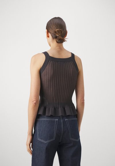 Brown ribbed tank top with a flared hem and wide straps, paired with dark blue denim jeans featuring contrasting white stitching.