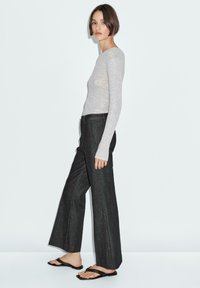 Gray ribbed long-sleeve top, high-waisted dark gray wide-leg pants, and black flip-flops, set against a plain light background.