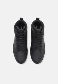 Black mid-top sneakers made of smooth leather; feature round laces, reinforced eyelets, and a subtle logo on the tongue.
