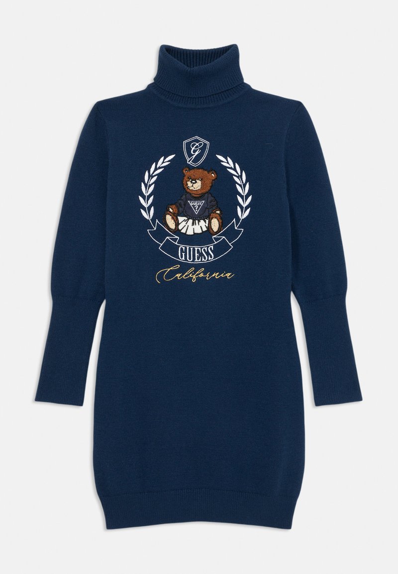 Jūros laivyno turtlneko suknelė su išsiuvinėtu meškiuko logotipu, apsuptu laurų lapų, su "Guess California" tekstu auksinės spalvos rašmenimis.