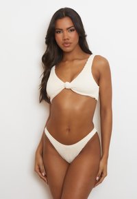 Virkat bikini-set i krämfärg, med en texturerad bralette med en central knutdetalj och matchande högskurna bikiniunderbyxor.