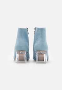 Hellblaue Wildleder-Stiefeletten mit klarem Blockabsatz und seitlichen Reißverschlüssen, mit glatter Textur und einfachem Design.