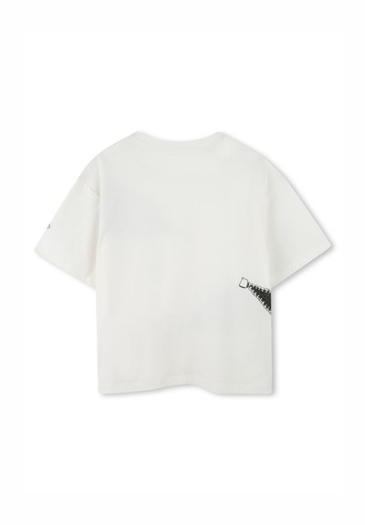 Biała bawełniana koszulka z luźnym krojem, krótkimi rękawami i kontrastowym czarnym zamkiem po lewej stronie w pobliżu dołu.