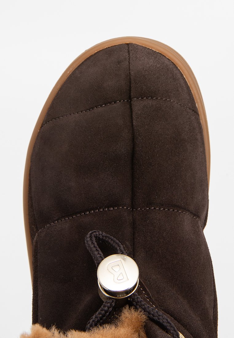 Braune Wildlederstiefel mit runder Zehenpartie, gestepptem Design und gummierter Sohle in Tan. Mit einem Kunstfellfutter und einem metallischen Akzent in der Nähe der Schnürsenkel.