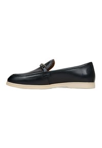 Zwarte lederen loafers met een tan rubberen zool, voorzien van een decoratieve zilveren metalen gesp en een glad, gepolijst afwerking.