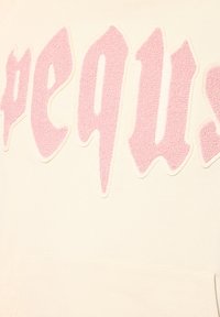 Cremfarbener Pullover mit einem großen, pinken, strukturierten, flauschigen Applikationslogo mit der Aufschrift "spegus" auf der Vorderseite. Mit einer Kängurutasche.