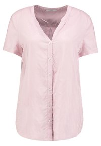 Blouse courte à manches courtes de couleur rose pâle, avec un devant à boutons, un motif à pois subtil et une texture douce et lisse. Design à encolure en V.