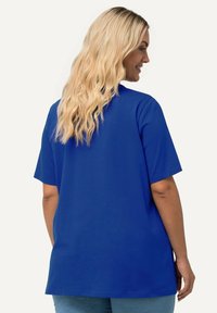Camiseta azul de gran tamaño con mangas cortas, escote redondo y una textura suave. El diseño es casual y sin adornos, adecuado para el uso diario.