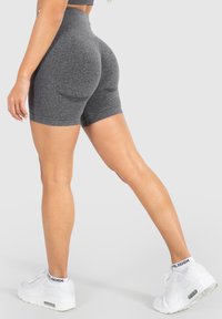 Shorts gris taille haute au design ajusté. Le tissu a une texture lisse, complétant des baskets de sport blanches.
