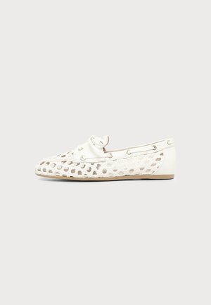 Chaussure mocassin en cuir blanc tissé avec motif ajouré, semelle basse plate et détails de lacets autour du bord supérieur.