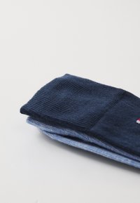 Marineblaue und hellblaue Baumwollsocken aufgestapelt, mit geripptem Muster, einfarbigem Design und einem kleinen Logo im hellblauen Abschnitt.
