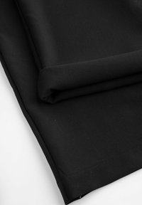 Czarny materiał starannie złożony, o gładkiej fakturze i czystych krawędziach, odpowiedni do różnych zastosowań, takich jak odzież lub tapicerka.