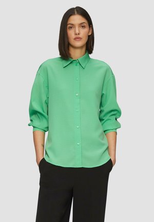 Groene, gestructureerde button-up shirt met een kraag en lange, opgerolde mouwen, gecombineerd met zwarte broek.