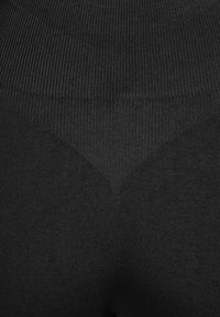 Gros plan sur un tissu noir texturé avec des motifs en tricot côtelés et lisses formant un motif en chevron.