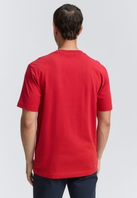 Rød bomulds T-shirt med rund hals og korte ærmer. Bagsiden har en glat tekstur og et enkelt design uden synlige grafikker.