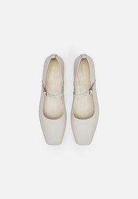 Zapatos estilo Mary Jane en color beige con punta cuadrada, parte superior de cuero suave, correa ajustable y un diseño liso y minimalista.