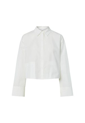 Camisa blanca de manga larga recortada con cuello puntiagudo, botones frontales ocultos y puños anchos sobre un fondo liso.