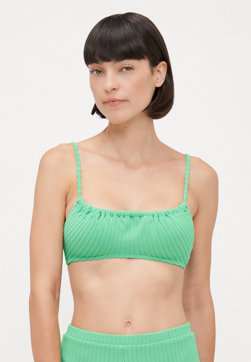 Top bikini verde a costine con spalline sottili, dettagli arricciati e finitura testurizzata. Tessuto morbido con un design senza cuciture.