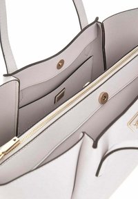Borsa a sacco grigia chiara con chiusura a zip, dotata di accessori in finitura dorata, tasche interne e bordi scuri a contrasto. Texture liscia su tutta la superficie.