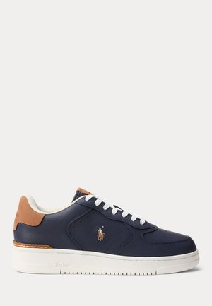 Sneaker bassa blu navy con suola bianca, lacci bianchi, linguetta al tallone color cuoio e logo Polo ricamato sul lato.