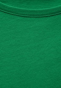 Grön bomullströja med rund halsringning. Tyget har en fin, slät textur och en enhetlig, livfull färg utan mönster eller grafik.