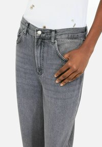 Faded gray denim jeans featuring a classic five-pocket design and button closure. The fabric has a subtle texture with a medium weight.