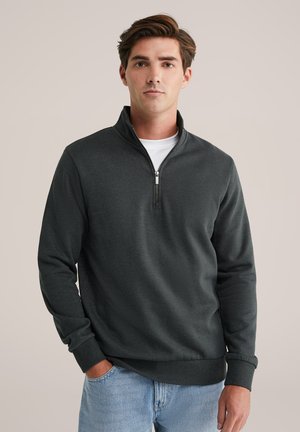 Pulover de culoare gri închis cu fermoar la gât, confecționat dintr-un material moale, având mâneci lungi, manșete cu nervuri și un design simplu de o culoare uniformă, fără modele.