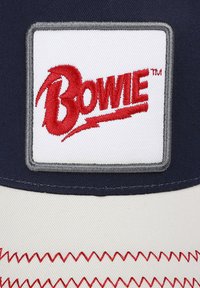Navy cap with a white patch featuring red embroidered text "Bowie." Includes gray border and red zigzag stitching on the brim.