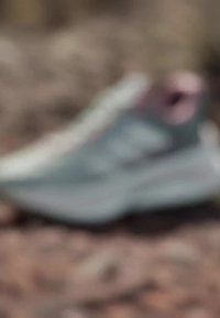 Scarpa atletica azzurro chiaro con suola bianca spessa, parte superiore testurizzata e dettagli rosa sul tallone e sulla linguetta. Materiale morbido al tatto.