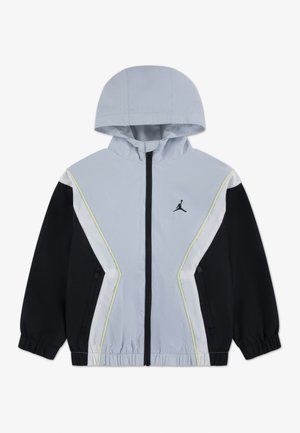 Lichtgrijs en zwart zip-up hooded jack met lange mouwen, zijzakken, elastische manchetten en een zwart Jumpman-logo op de borst.