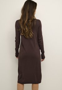 Robe marron à manches longues au design ajusté, confectionnée en matière douce. Dotée d'un col et de poignets côtelés, elle tombe jusqu'au mi-mollet.