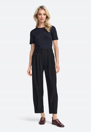 Pantaloni neri su misura con vita alta e gambe larghe, abbinati a un top blu navy aderente e scarpe borgogna con lacci. Texture lisce in tutto.