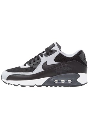 Baskets Nike Air Max noir et blanc avec tige en mesh, coussin d'air visible dans la semelle, lacets noirs et logo swoosh emblématique sur le côté.
