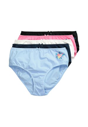 Femme souriante posant les mains sur les hanches, portant un soutien-gorge bleu foncé et un sous-vêtement taille haute blanc avec broderies florales.