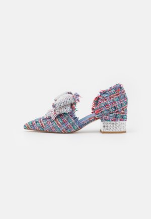 Zapato de bajo tacón de tela trenzada multicolor con punta afilada, adornado con un gran lazo de cuentas plateadas y un tacón de bloque con piedras brillantes.