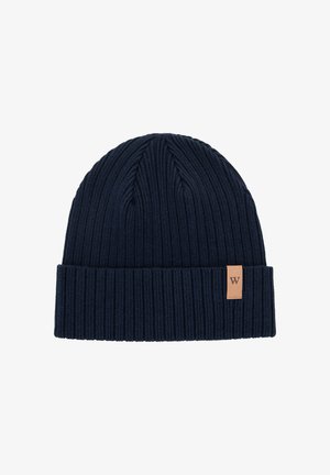 Granatowa dzianinowa czapka z prążkowaną teksturą i mankietem. Z boku znajduje się skórzana metka z wytłoczonym logo.